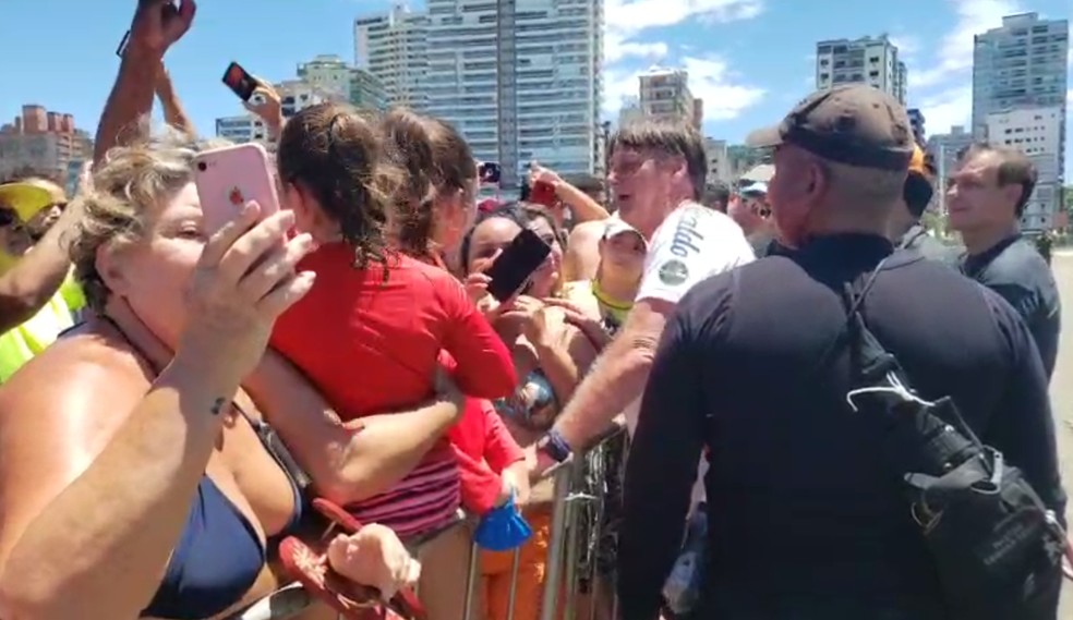 Sem máscara, Bolsonaro provoca aglomeração em praia de SP, abraça banhistas e pega crianças no colo