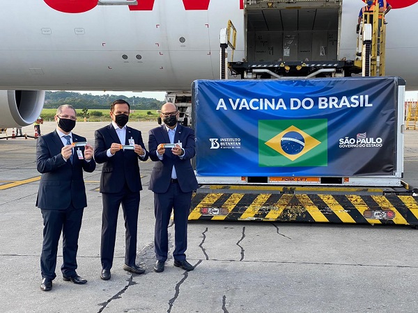 Doria recebe insumos da Coronavac em aeroporto com faixa vacina do Brasil