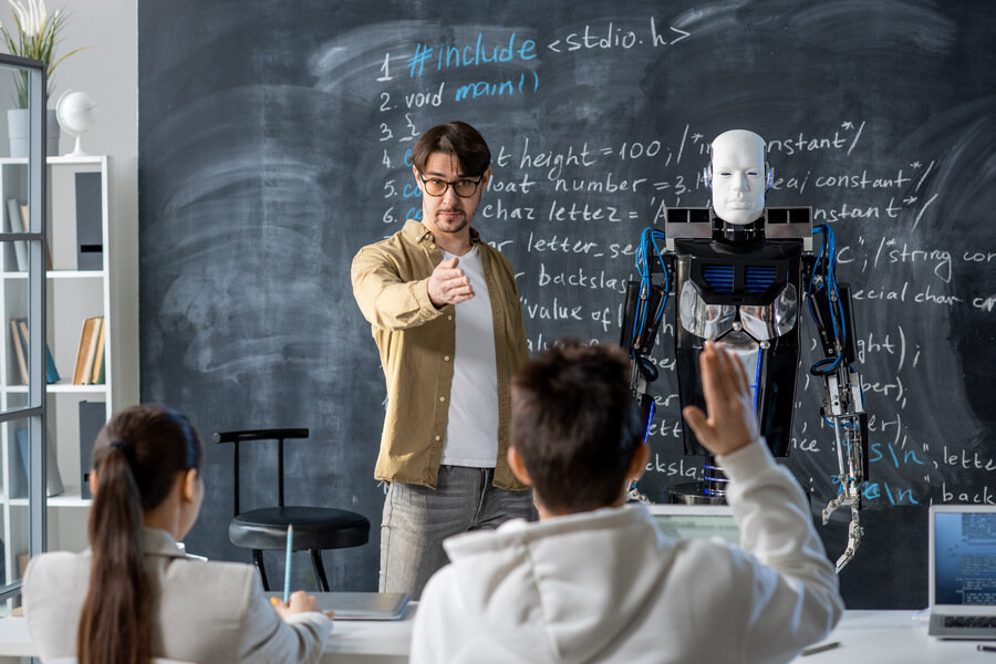 Contemporary teacher pointing at one of students wanting to ask question about characteristics of robot standing by blackboard