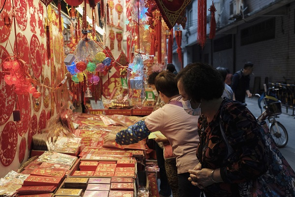CANTÃO, CHINA, 08.02.2021 - Uma mulher procura itens decorativos chineses, na véspera do Ano-Novo chinês, em Cantão, na China. (Foto: Diego Herculano/Folhapress)