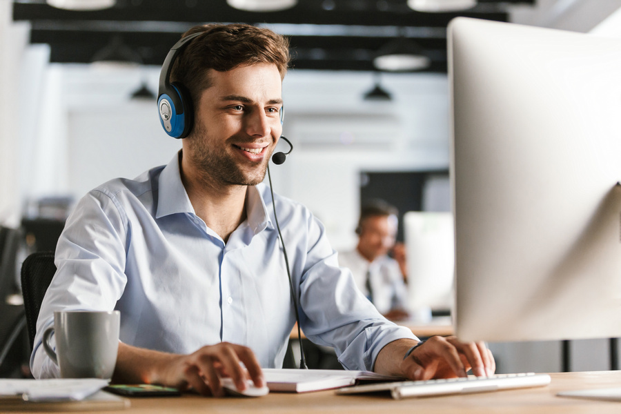 Photo of young worker man 20s wearing office clothes and headset smiling and talking with clients in call center